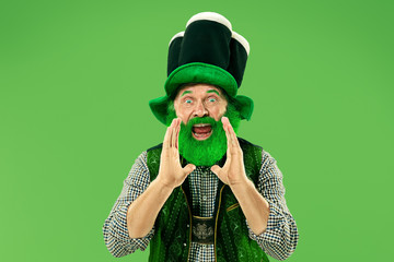 A smiling surprised happy senior man in a leprechaun hat with beard at green studio. He celebrates...