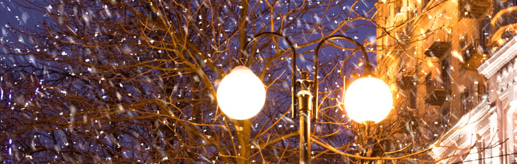 lantern on a dark blue night sky and falling snow.
