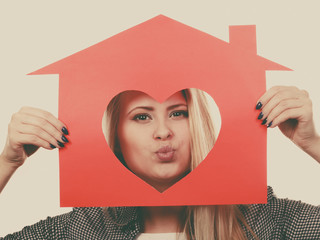 Funny girl holding red paper house with heart shape