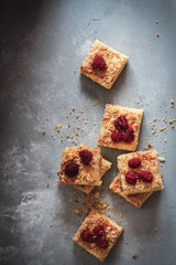 Sliced homemade cake with frozen raspberries on top on the dark background