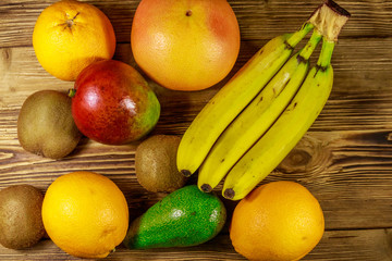 Assortment of tropical fruits on wooden table. Still life with bananas, mango, oranges, avocado, grapefruit and kiwi fruits