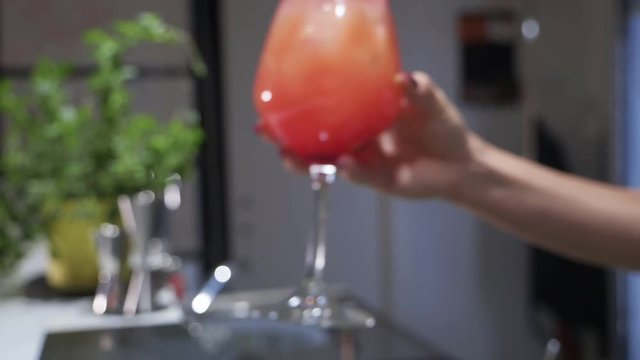 waitress hands serving glass of Negroni cocktail at the bar counter- slow motion