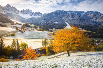 Obraz premium Funes valley and Santa Magdalena village during late autumn with colorful cherry trees and snow. Santa Magdalena, Funes Valley, South tyrol, Italy.