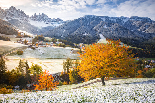 Funes valley and Santa Magdalena village during late autumn with colorful cherry trees and snow. Santa Magdalena, Funes Valley, South tyrol, Italy.