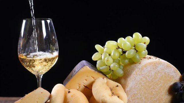 Restaurant cheese art. Variety of hard cheese put in a beautifully composition. Wine is pouring into a flass in slow motion. Wine and appetizer concept. Luxury restaurant concept. Food art. hd