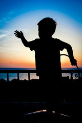 Fototapeta premium Happy child at the time of the silhouette of the sea background