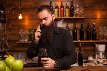 Bartender behind the counter enjoying a glass of wine and talking on the phone.