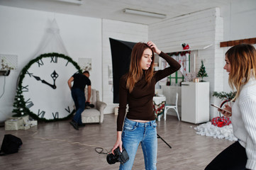 Young photographer girl discussing with anonther worker at studio.