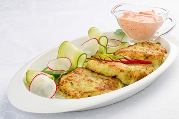 Zucchini pancakes with sauce on a white plate