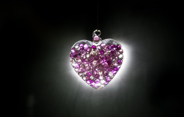 Valentines Day Concept. Glass transparent heart on dark. Crystal heart in the dark, glass heart glows, glass painting, black background