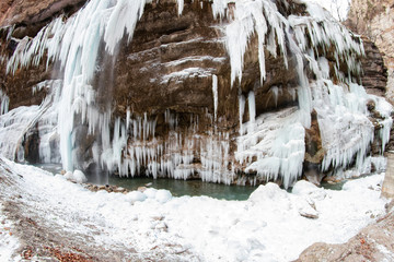 Fototapeta na wymiar Large frozen icicles on site of waterfalls in mountainous area