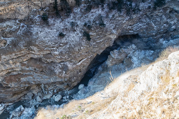 The view from the top of the cliff down into a ravine, through which flows a mountain river