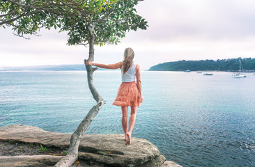 Girl looking out to see holding on to lone tree wind in her hair