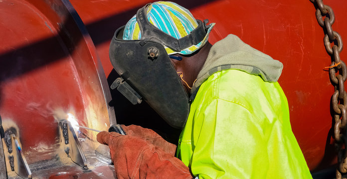 Man welding metal on a construction site, Tradesman working with welding torch