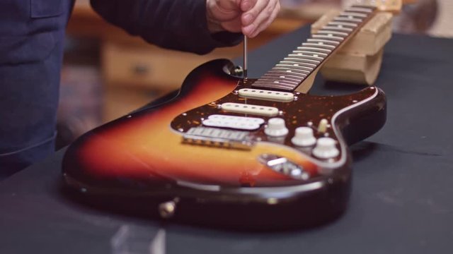 Man repairs guitar with a screwdriver