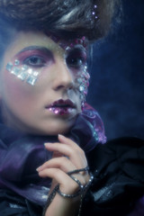 portrait of woman with artistic make-up in blue smoke