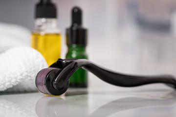 Dermaroller, Handtuch, gelbe Pflege Öl und grüne Serum Flaschen zum  Microneedling für Anti...