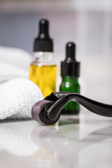 Dermaroller, Handtuch, gelbe Pflege Öl und grüne Serum Flaschen zum  Microneedling für Anti...
