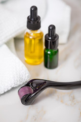 Dermaroller, Handtuch, gelbe Pflege Öl und grüne Serum Flaschen zum  Microneedling für Anti...