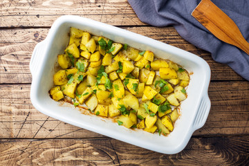 Potatoes baked with spices and herbs in a ceramic baking tray. Vegetarian cuisine.