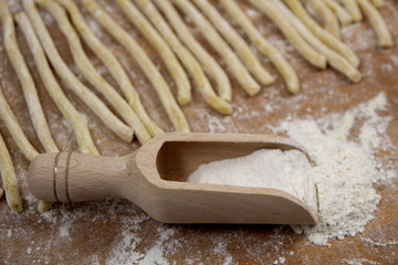 Homemade fresh uncooked Italian pasta fusilli with flour on wooden background
