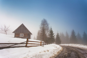 Lone house in mountain village. Foggy weather and melting snow