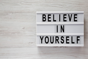 'Believe in yourself' words on modern board on a white wooden background, top view. From above, flat lay, overhead. Copy space.