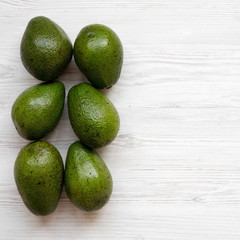 Whole avocados on white wooden background, top view. Flat lay, overhead, from above. Space for text.