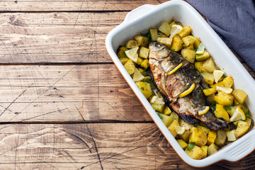 Baked fish carp with potatoes in a ceramic pan. Rustic style. Copy space