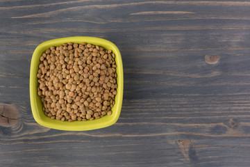 Yellow lentil in a bowl on wooden background