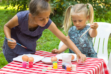 Two kids painting Easter eggs outdoors