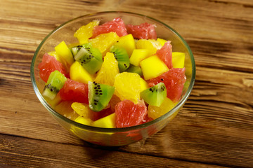 Tasty fruit salad in glass bowl on the wooden table