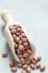 Dry pinto beans in wooden scoop, copy space, vertical