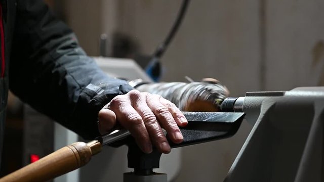 handicraft man edits a rotating piece of wood on turnery machine