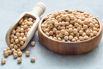 Dry chickpeas in a wooden bowl and in the scoop, horizontal