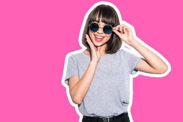 Collage in magazine charming young woman in sunglasses with hand on chin isolated on pink background