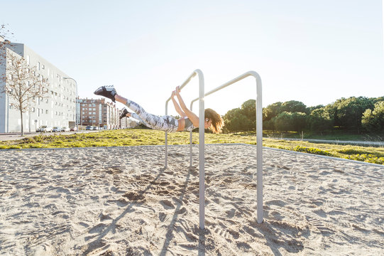 Woman training on parallel bars on street