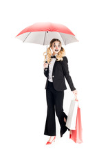 smiling female clown holding shopping bags and umbrella isolated on white