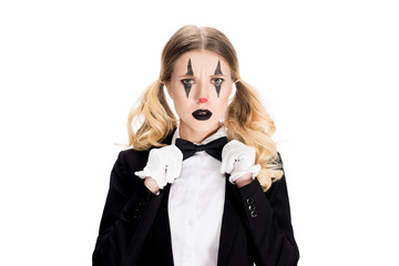 sad female clown standing in suit and touching bow tie isolated on white