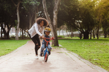 Mom teaching her son biking at park - Powered by Adobe