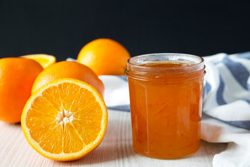 Homemade orange marmelade in glass jar, side view.
