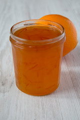 Homemade orange marmelade in glass jar on a white wooden background, side view. Closeup.