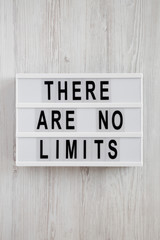 Modern board with text 'There are no limits' on a white wooden background, top view. Flat lay, overhead.