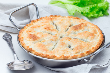 Vegetarian pot pie with lentil, mushrooms, potato, carrot and green peas, covered with puff pastry, in baking dish, horizontal