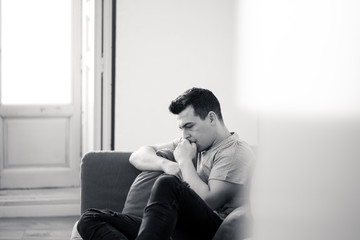 Young man suffering from depression lying on sofa alone at home feeling frustrated and hopeless