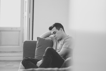 Fototapeta premium Young attractive man suffering from depression in emotional pain lying on couch at home