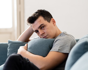 Young man suffering from depression lying on sofa alone at home feeling frustrated and hopeless