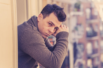 Unhappy man suffering from depression feeling desperate, isolated and worthless on home balcony