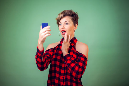 People and emotions - a portrait of smiling woman with short hair looking at mirrow and correcting makeup