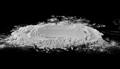 Wheat flour pile isolated on black background, powder texture